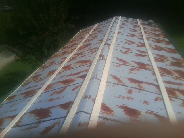 Rusted metal roof panels with new wood purlins before replacement — Storm Damage Roof Repair in Lansing by Roofing Brothers